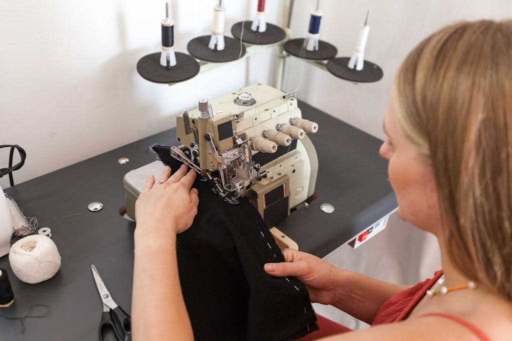 Woman sewing in a fashion design studio, using a professional machine to create garments.
