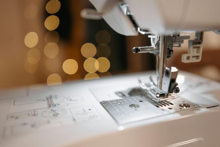 Detailed view of a sewing machine needle and parts with bokeh background, showcasing precision engineering.